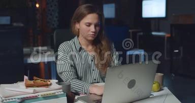 前景看到漂亮的<strong>女</strong>办公室工作人员在她的笔记本电脑上打字<strong>深夜</strong>。 年轻<strong>女</strong>子用她的电脑