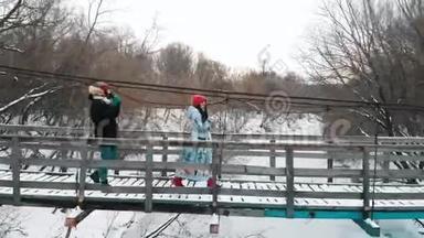 两个年轻的女人从热水瓶里喝热饮料，走在桥上