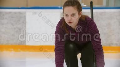 冰场上的卷发训练-一个年轻的女人用石头从看台上