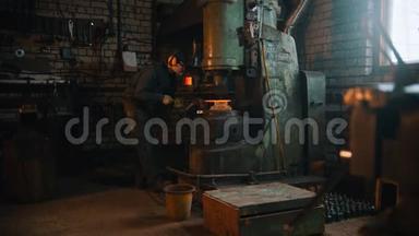 锻造工业-一个铁匠在车间里用大型工业压力机工作