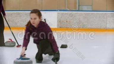 冰场上的卷发训练-一个年轻的女人用石头咬人从看台上推开