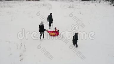 <strong>一家人</strong>在冬天的田野上玩耍-父亲骑着儿子的充气雪橇，他的妻子和<strong>女儿</strong>追赶