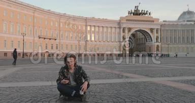 这位美丽的年轻人坐在皇宫广场上，日落时分喝咖啡，他穿着一件军服，