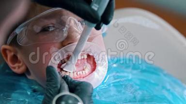 一个戴防护眼镜的小男孩在现代牙科中进行清洁治疗-用吸管收集水