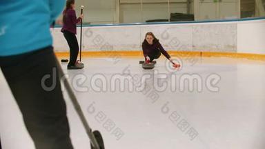 卷曲训练-一个女人用花岗岩石头在冰场上滑冰并释放它