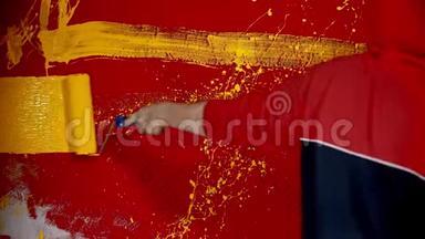 一个穿着帽衫的男人走在<strong>红墙</strong>边，用油漆滚筒画黄色的线条