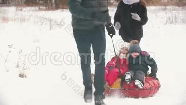 一家人在森林附近的户外跑步-男人把他的孩子卷在充气雪橇上