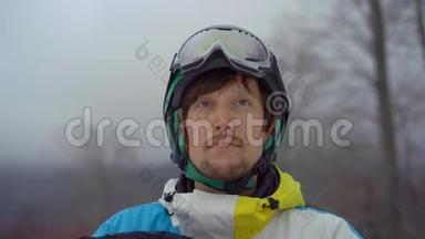 一个年轻人戴着头盔，在一个山区<strong>度假胜地</strong>用滑雪板拍摄的特写镜头。 他戴上他的雪谷歌。 <strong>冬季</strong>