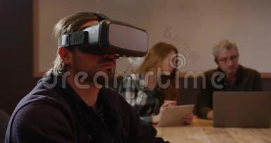 男士戴着VR耳机，同事在创意办公室工作