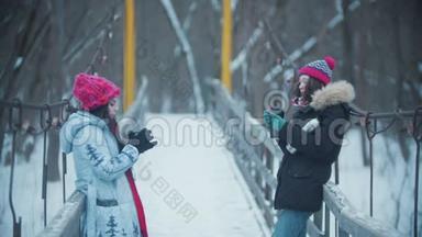 两个年轻的女人站在雪桥上聊天——从<strong>热水</strong>瓶里<strong>喝</strong>热饮料