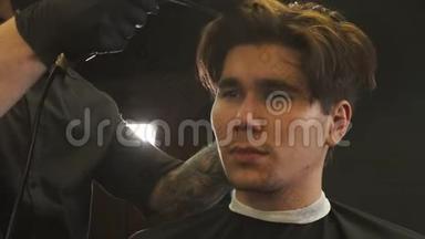 一位年轻英俊的男子正在接受纹身男理发师的服务——理发后把头发擦干