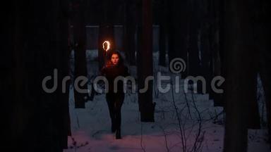 一个年轻的被吓坏了的女人，手里拿着火炬在夜间的冬林里躲避危险