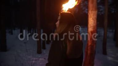 一个<strong>年轻的</strong>被<strong>吓坏了的</strong>女人，手里拿着火炬在森林里躲避危险