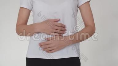 一个女人的腹部的<strong>特写</strong>，一个女人把她的手并挤压它。 一个穿白色t恤穿白色的年轻女人