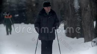 一位年迈的祖父-祖父正在一个冬季公园里散步，四处张望