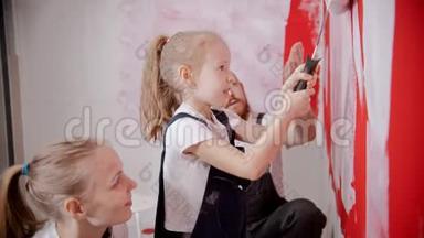 爸爸妈妈教他的小女儿如何正确地粉刷墙壁