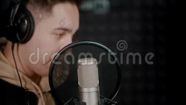 一个年轻的说唱歌手在录音室录制他的曲目并享受这个过程
