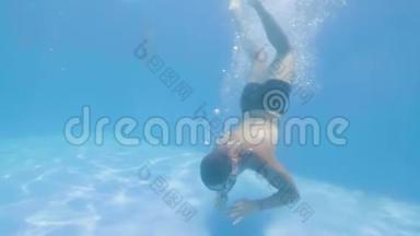 水下观景男子游泳运动员在蓝水游泳池潜水。 年轻人跳在漂浮的游泳池里游泳