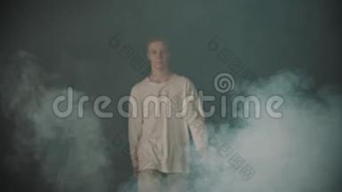 年轻的舞蹈演员从黑暗的工作室里的烟雾中走出来