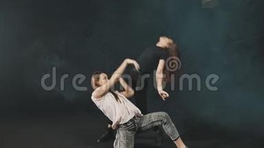 两个年轻女子在黑暗的工作室里训练舞蹈