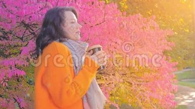 美丽的女孩在秋天的花园里喝茶，穿着羊毛衫