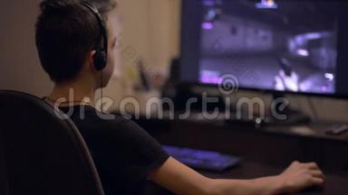 青少年男孩在桌面电脑上玩在线射击游戏。