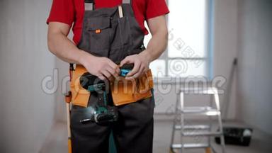 一个年轻的工人从他的工作服上拿出一个标尺
