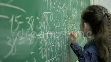 小学。 小女生在教室的绿色黑板上写数字