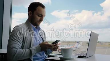 商人在<strong>机场</strong>候机室用笔记本电脑工作时检查他的手机。