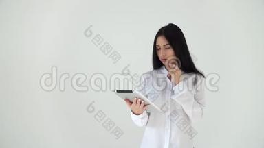 一个体贴的女孩在电脑平板上翻阅新闻。 一位穿着白色衬衫的商务女士，在一个数码公司工作