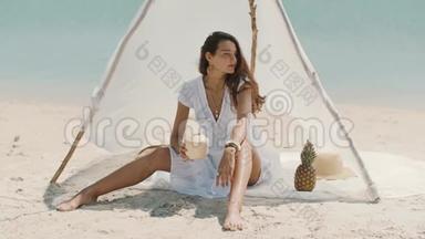 女人一边喝<strong>椰子汁</strong>一边在海滩上放松