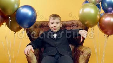 严肃的男孩用手<strong>坐</strong>在椅子上，用黄色的<strong>气球</strong>表示不喜欢的迹象