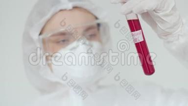 一位年轻的女科学家检查一个红色的试管。 戴化学<strong>防</strong>护、安全<strong>眼镜</strong>和呼吸器的妇女