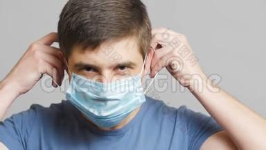一位年轻医生的脸在灰色的工作室背景上戴上外科口罩，医学和健康的概念，检疫