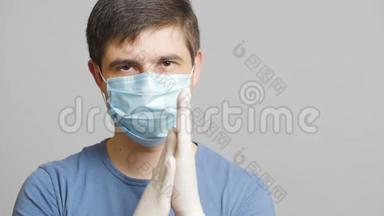 戴着幽默的外科口罩，戴着灰色背景的无菌手套，狡猾地搓手，概念医学笑话，奇怪的医生