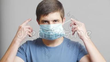 一位年轻医生的脸在灰色的工作室背景上戴上外科口罩，医学和健康的概念，检疫