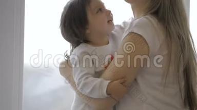 可爱的小女孩拥抱着她美丽的<strong>怀孕妈妈</strong>`肚子，微笑着