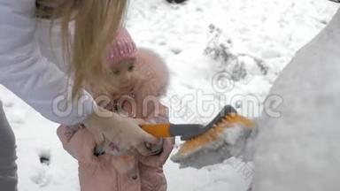 可爱的小孩帮着刷车上的雪。 幼儿拿着清洁工具
