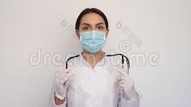 戴着白色医疗手套和防护面罩的女医生在他的脖子上放了一个听诊器，人和医学概念