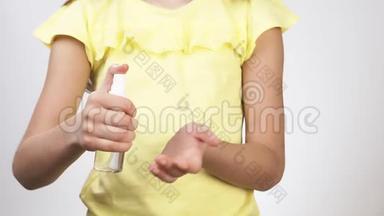 小孩子用防腐剂处理他们的手。 一个小女孩在她的手上喷洒了一种防腐剂