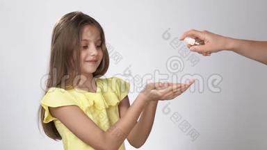 小孩子用<strong>防腐</strong>剂处理他们的手。 一个小女孩在她的手上喷洒了一种<strong>防腐</strong>剂