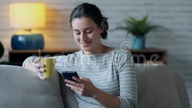 微笑的年轻<strong>女子</strong>使用她的手机，而<strong>坐在沙发上</strong>的客厅在家里。