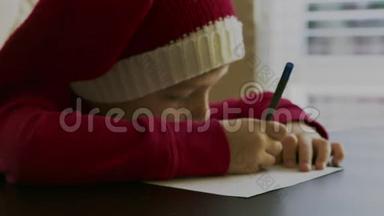 小男孩穿着红色的毛衣，戴着一顶红色的圣诞帽，手里拿着一支笔，头上戴着白色的柚子