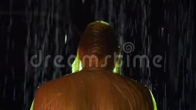 穿着雨衣的人站在前台，水在背景中倾泻，或者下雨。 戏剧