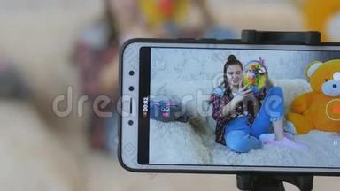 在智能手机上录制视频博客的视频。 一个十几岁的女孩在智能手机相机上讲述一些事情。