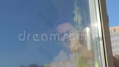 一个女人在肮脏的表面喷洒洗涤剂，用抹布擦拭窗户，从而清洗她的窗户。