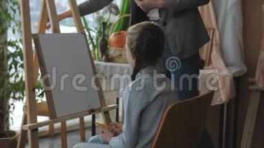 艺术工作室的<strong>老师</strong>教孩子们，坐在画架前的女孩仔细听<strong>老师</strong>的话。