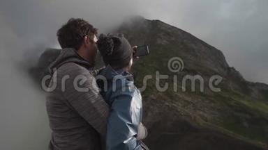 一对年轻夫妇在悬崖上拥抱拥抱，拍了一张自拍照片