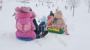 快乐的孩子们从雪下的山坡上骑马。 观念寒假家庭放假，生活方式健康，心情开朗..