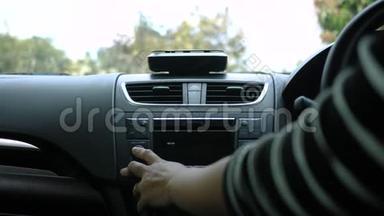 阳光明媚的一天，年轻女子开着一辆车，在车上转动收音机<strong>按钮</strong>。